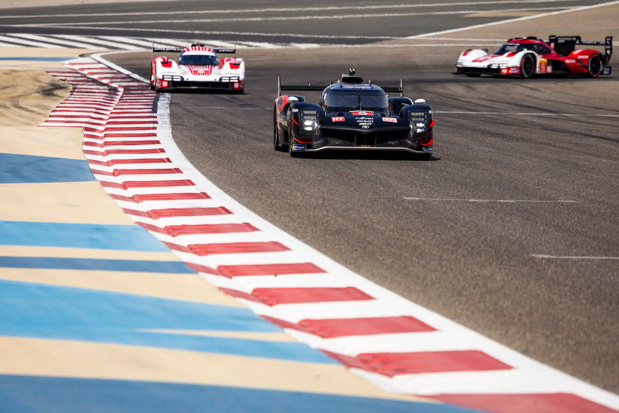 A Toyota followed by two factory Porsche 963s, exiting turn 10 at Bahrain. Image: Julien Delfosse / DPPI