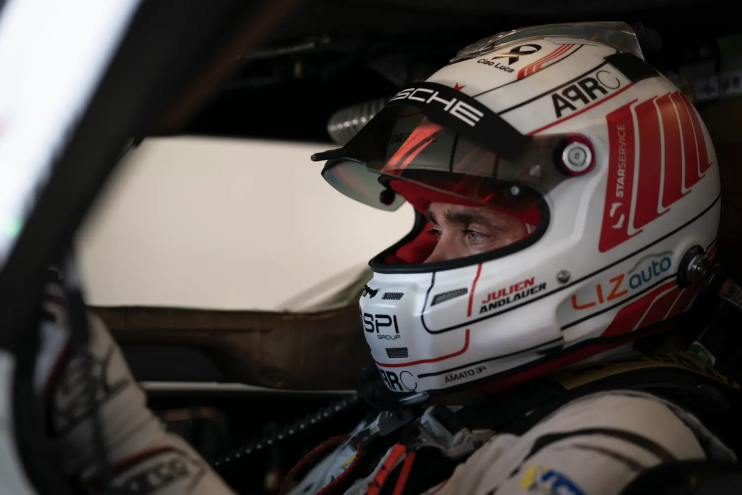 Julien Andlauer in the cokpit of the #99 Proton Porsche, with his helmet on and visor up.